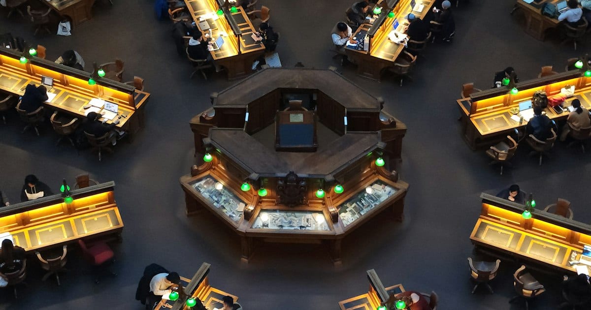 An exchange trading floor seen from above, desks arranged in a ring under bright lights.